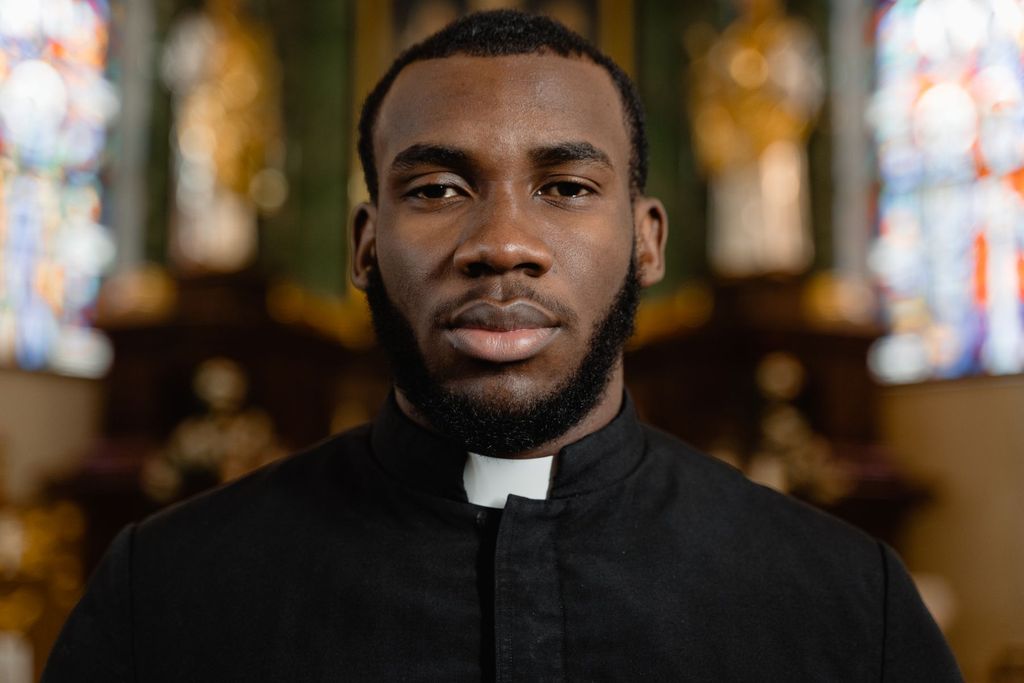 Portrait of a priest in front of a stained glass window