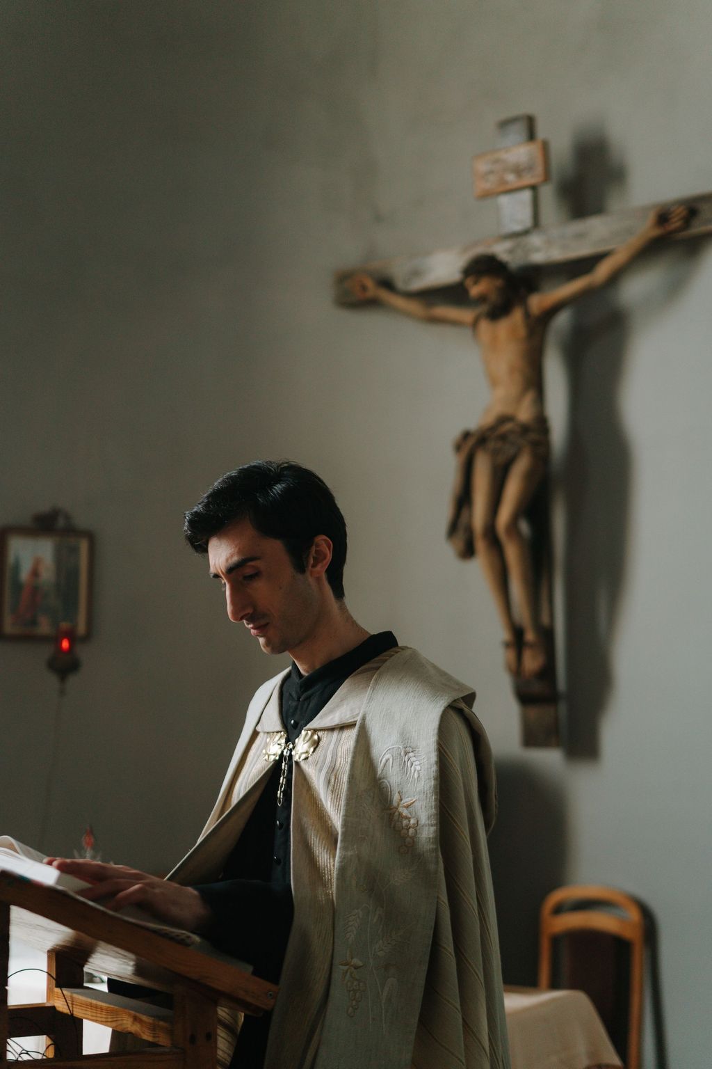 A young man in an alb reading at the ambo