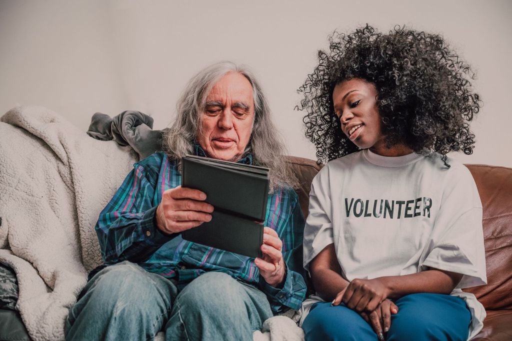A volunteer helping a senior with a tablet